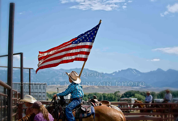 A young cowboy holding the flag before the start of the ranch rodeo